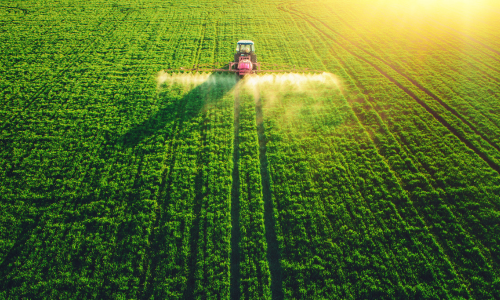 Tractor spraying chemicals over a field